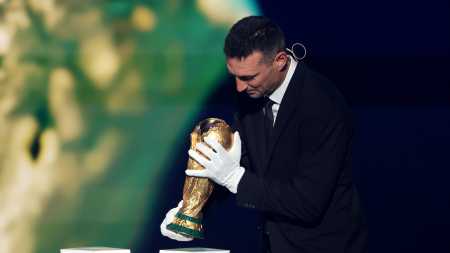 Lionel Scaloni, técnico da Argentina, usa luvas ao segurar taça da Copa do Mundo • Divulgação/Argentina