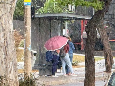 Mulher utilizando sombrinha durante chuva forte em BH