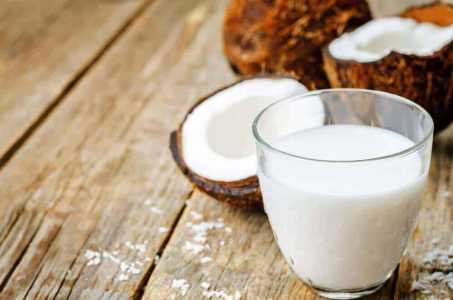 Cocos e leite de coco, em um copo, em cima de uma mesa de madeira