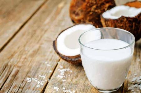 Cocos e leite de coco, em um copo, em cima de uma mesa de madeira