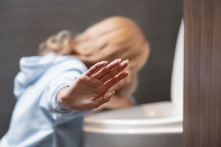 Mulher vomitando em vaso sanitário