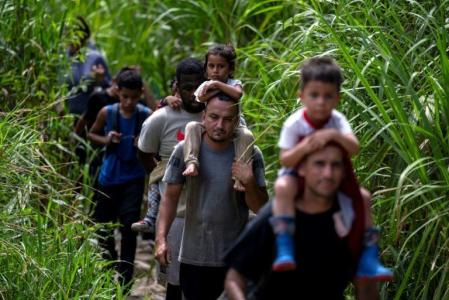 Migrantes com crianças nos ombros caminham pela selva perto da cidade de Bajo Chiquito, primeiro controle de fronteira da província de Darién, Panamá, em 22 de setembro de 2023