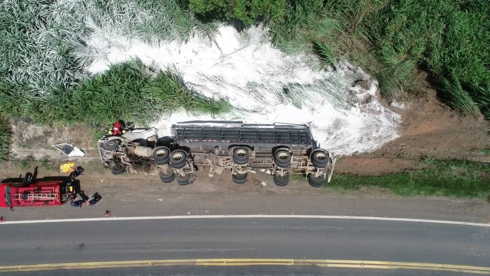 Carreta de cal tomba e motorista fica ferido preso às ferragens na MG-050