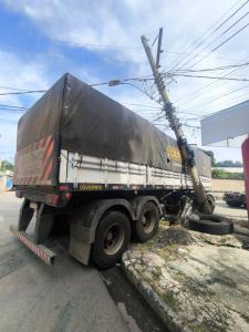 A colisão deixou o poste pendurado, apoiado no caminhão que o atingiu