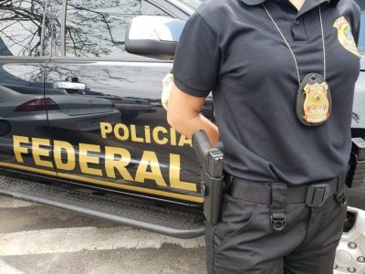 Policial em frente a carro da Polícia Federal