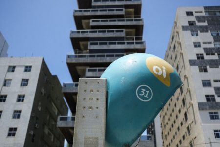 A public phone from Brazilian telephone operator Oi SA is seen between buildings in the city of Recife, in northeast Brazil, on November 6, 2017. Recently, Oi SA shares rose sharply with news of a joint offer from China Telecom and the US fund TPG, which would be willing to invest R$ 10 billion in the company. (Photo by Diego Herculano/NurPhoto) (Photo by Diego Herculano / NurPhoto via AFP)