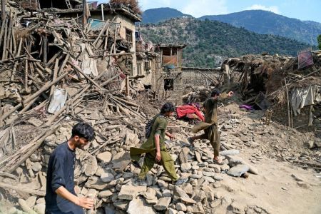 Afegãos caminham em frente a casas destruídas após terremotos na vila de Mazar Dara, no distrito de Nurgal, província de Kunar, no leste do Afeganistão, em 1º de setembro de 2025.