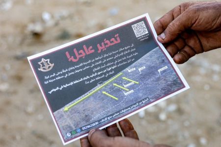 Um homem segura um dos panfletos lançados pelo exército israelense na Cidade de Gaza, pedindo evacuação para o sul, para al-Mawasi, em 9 de setembro de 2025.