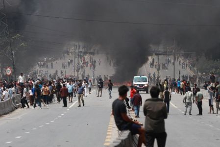Um incêndio arde enquanto manifestantes se reúnem numa estrada durante um protesto para condenar a repressão mortal da polícia aos manifestantes em Katmandu, em 9 de setembro de 2025, um dia depois das manifestações contra as proibições das redes sociais e a corrupção por parte do governo.