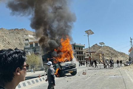 Uma viatura policial incendiada pelos manifestantes é fotografada em uma rua perto da sede do Partido Bharatiya Janata (BJP) em Leh, em 24 de setembro de 2025