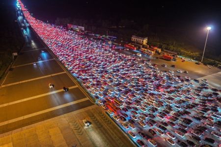 Motoristas entram nas faixas da via expressa após passarem pelo posto de pedágio de Wuzhuang em Chuzhou, na província de Anhui, no leste da China, enquanto retornam para casa no penúltimo dia de um feriado de oito dias do Dia Nacional, em 7 de outubro de 2025