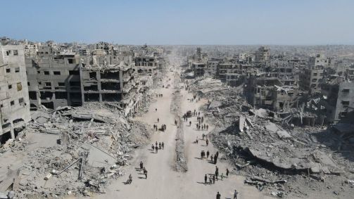 Nesta vista aérea, pessoas caminham em meio à destruição na Cidade de Gaza, no norte da Faixa de Gaza, em 11 de outubro de 2025, um dia após a entrada em vigor de um cessar-fogo.