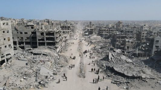 Nesta vista aérea, pessoas caminham em meio à destruição na Cidade de Gaza, no norte da Faixa de Gaza, em 11 de outubro de 2025, um dia após a entrada em vigor de um cessar-fogo.