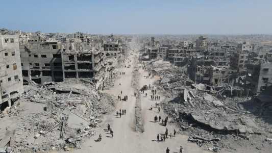 Nesta vista aérea, pessoas caminham em meio à destruição na Cidade de Gaza, no norte da Faixa de Gaza, em 11 de outubro de 2025, um dia após a entrada em vigor de um cessar-fogo.