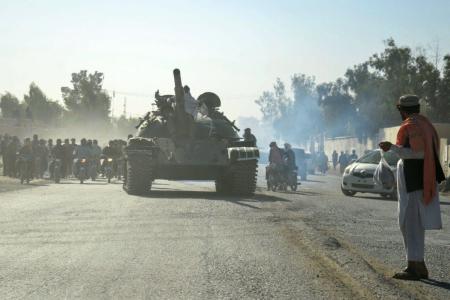 Agentes de segurança do Talibã em um tanque da era soviética são seguidos por motociclistas enquanto dirigem-se para a fronteira, durante confrontos em andamento entre agentes de segurança do Talibã e forças de fronteira paquistanesas, no distrito de Spin Boldak, na província de Kandahar, em 15 de outubro de 2025
