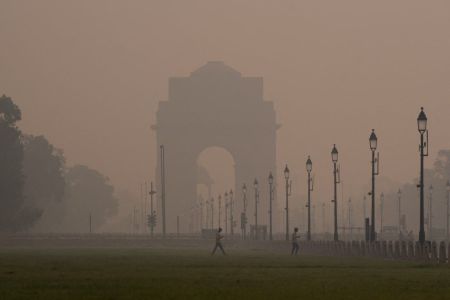 Pedestres caminham em um parque perto do Portão da Índia em meio à neblina em Nova Délhi, Índia, em 22 de outubro de 2025. Uma densa neblina cobriu a cidade dois dias após as celebrações de Diwali, com o índice de qualidade do ar de Délhi caindo para 345 às 5h30, classificando-a na categoria "muito ruim"