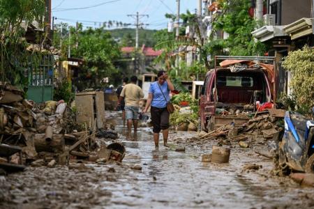 Uma mulher caminha por uma rua coberta de lama após a passagem do tufão Kalmaegi em Liloan, na província de Cebu, em 6 de novembro de 2025.