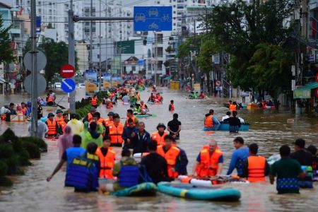 Esta foto, tirada em 20 de novembro de 2025, mostra pessoas caminhando em meio às águas da enchente em Nha Trang, na província costeira de Khanh Hoa, no Vietnã.