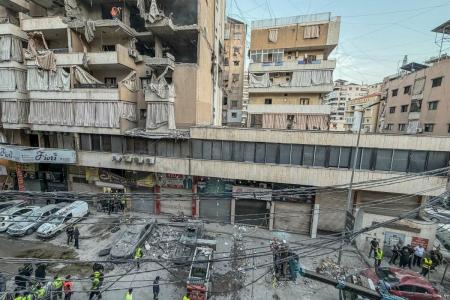 Operários limpam os escombros do local de um ataque aéreo israelense que teve como alvo um prédio residencial no bairro de Haret Hreik, no sul de Beirute, em 23 de novembro de 2025