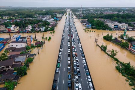 Esta foto aérea, tirada em 25 de novembro de 2025, mostra veículos estacionados em uma estrada elevada para protegê-los das águas da enchente em Hat Yai, na província de Songkhla, no sul da Tailândia, após graves inundações afetarem milhares de pessoas no sul do país depois de dias de fortes chuvas.