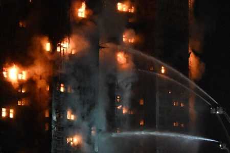 Testemunhas observam a densa fumaça e as chamas que se elevam durante um grande incêndio no conjunto residencial Wang Fuk Court, no distrito de Tai Po, em Hong Kong, em 26 de novembro de 2025