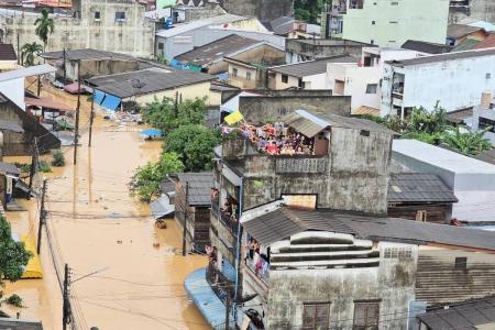 Esta foto, divulgada pela Marinha Real Tailandesa em 26 de novembro de 2025, mostra pessoas olhando de dentro de prédios residenciais cercados por águas da enchente em Hat Yai.
