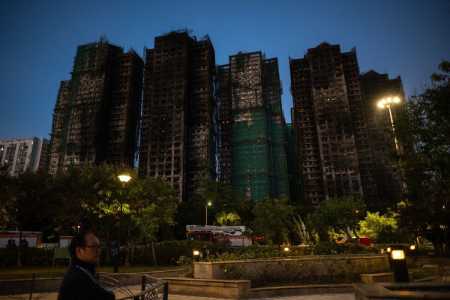 Um homem caminha em meio aos destroços de um grande incêndio que devastou vários blocos de apartamentos no conjunto residencial Wang Fuk Court, no distrito de Tai Po, em Hong Kong, em 28 de novembro de 2025