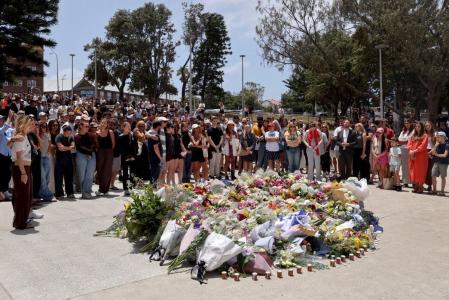 Pessoas em luto se reúnem junto a homenagens florais no Pavilhão de Bondi em memória das vítimas do tiroteio na praia de Bondi, em Sydney, em 15 de dezembro de 2025.