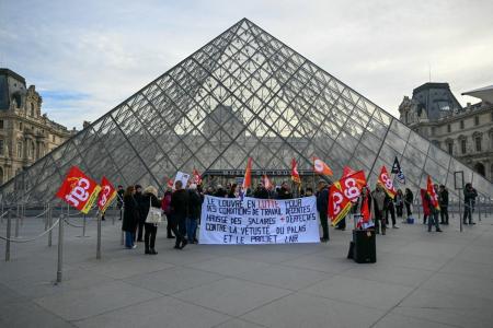 Membros do sindicato francês CGT protestam em frente à entrada do Museu do Louvre, em Paris, em 15 de dezembro de 2025, enquanto os trabalhadores votavam pela greve contra a deterioração das condições de trabalho e a piora da experiência dos visitantes no mundialmente famoso museu