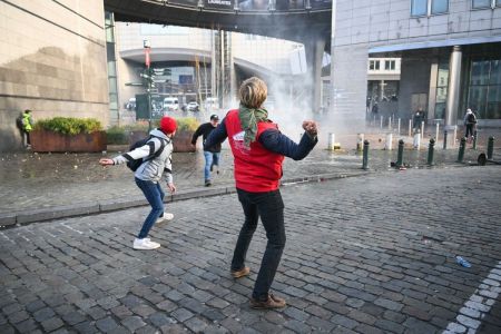 Um manifestante vestindo um colete da Jeunes Agriculteurs (JA, Jovens Agricultores) atira uma batata em direção ao Parlamento Europeu durante um protesto de agricultores para denunciar as reformas da Política Agrícola Comum (PAC) e acordos comerciais como o Mercosul, em Bruxelas, em 18 de dezembro de 2025, organizado pela Copa-Cogeca, a principal associação que representa agricultores e cooperativas agrícolas na UE
