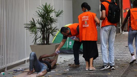Foto mostra agente da Prefeitura de Belo Horizonte oferecendo água potável para morador em situação de rua