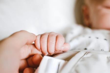 Bebê segura a mão da mãe