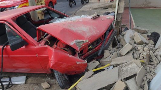 Imagem mostra carro vermelho após batida que destruiu muro