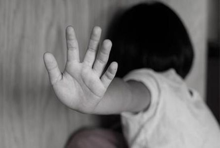 Criança tampa o rosto com a palma da mão