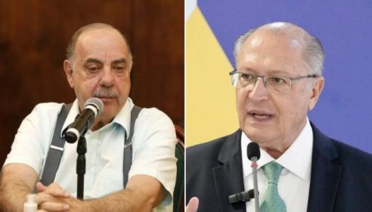 Fuad Noman é um homem branco, de bigode e cabelos brancos. Ele tem olhos claros e na imagem usa uma camisa social laranja claro com um suspensório cinza.