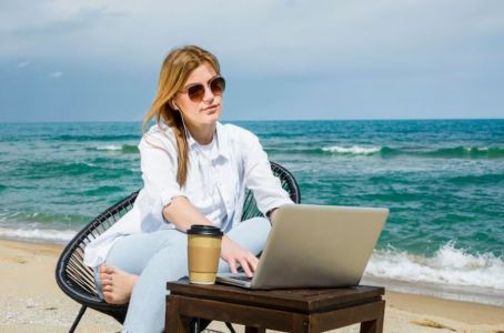 Mulher com óculos de sol trabalhando na praia