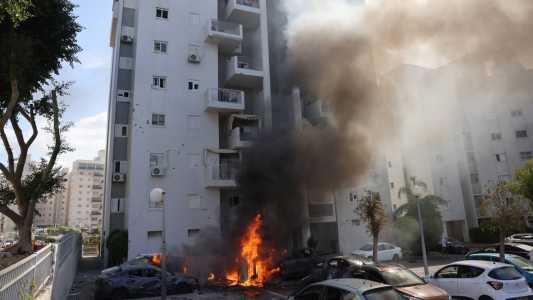 Carros em chamas em frente a prédio residencial em Ashkelon, Israel, após ataque do Hamas