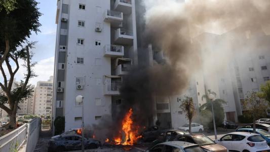 Carros em chamas em frente a prédio residencial em Ashkelon, Israel, após ataque do Hamas