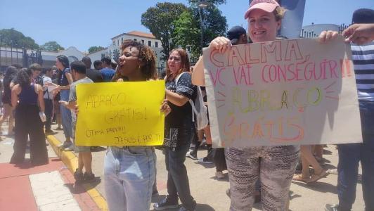 Cartazes na porta da PUC Minas anunciam 'abraço grátis' com desejos de uma ótima prova
