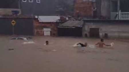 Foto mostra jovens nadando em alagamento durante chuva forte em Contagem, nesta quarta-feira (6)