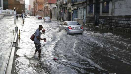 Foto mostra homem tentando atravessar rua alagada no Rio de Janeiro