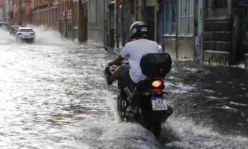 Foto mostra motociclista passando por rua alagada no Rio de Janeiro
