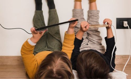 Crianças com dispositivos eletrônicos no carregador