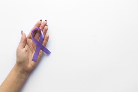 Mão segurando laço roxo, da campanha Maio Roxo