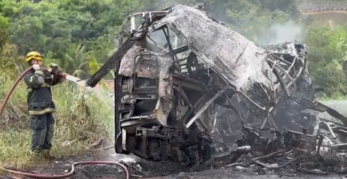 Bombeiros realizando trabalho de conter o fogo no ônibus envolvido em acidente 