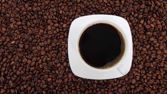 Grãos de café e xícara com café