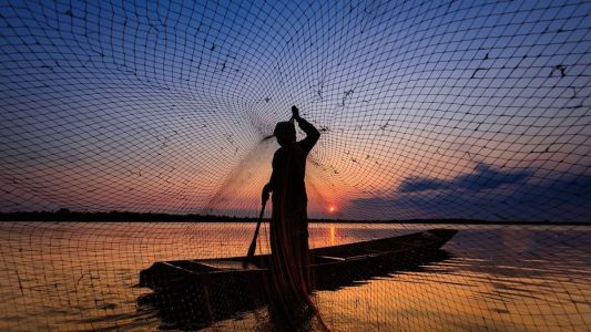 Pescador com rede em rio