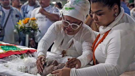 Viúva de Arlindo Cruz, Babi Cruz chorando próximo ao caixão ao lado da filha Flora Cruz