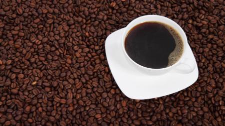 Grãos de café e xícara com café