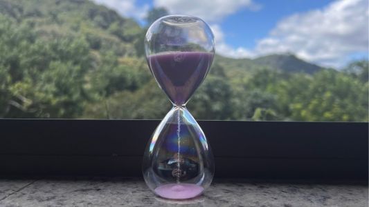 ampulheta em uma janela mostrando montanhas e céu ao fundo